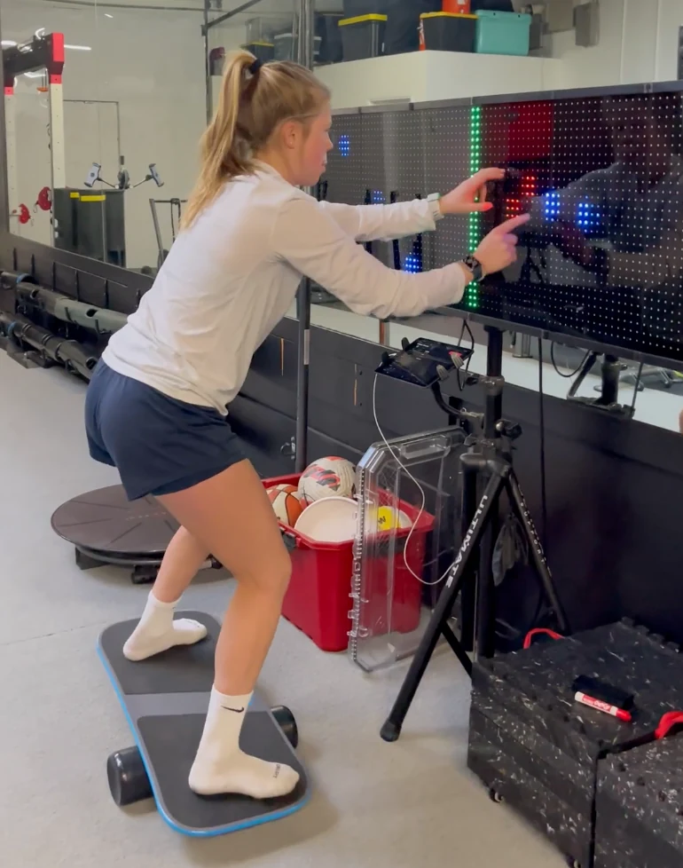 Athlete tapping Reflexion targets while standing on a balance board